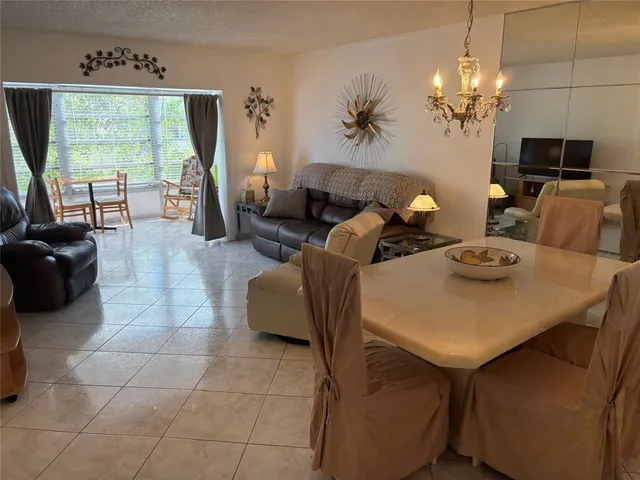 a living room with furniture a chandelier a large window and a flat screen tv
