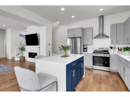 a kitchen with stainless steel appliances kitchen island granite countertop a stove a sink a refrigerator and a living room with a bookshelf