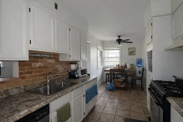 a kitchen with granite countertop a sink stove and cabinets