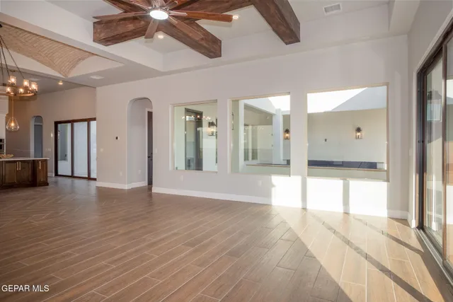 an empty room with wooden floor fireplace and windows