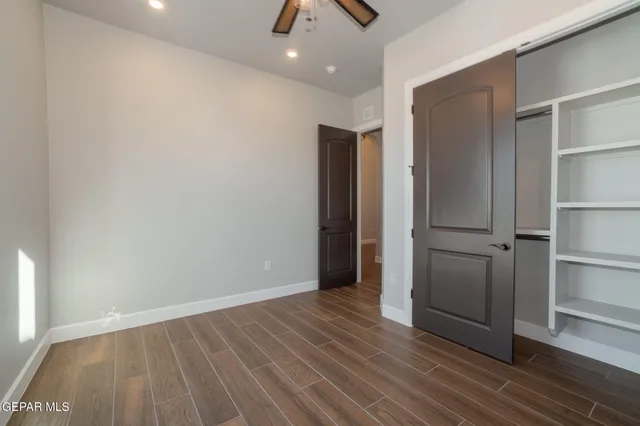 a view of an empty room with wooden floor and closet