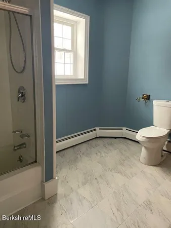 a bathroom with a granite countertop toilet and a shower