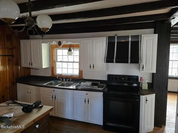 a kitchen with granite countertop a sink a stove and cabinets