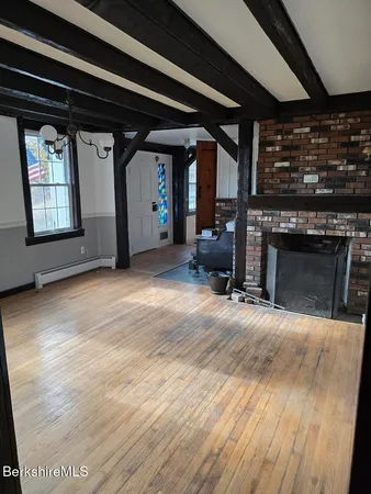 an empty room with wooden floor a fireplace and windows