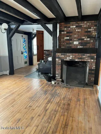 an empty room with wooden floor fireplace and windows