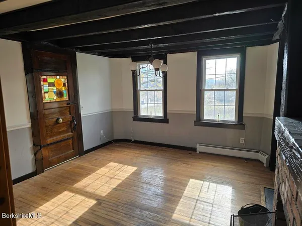 a view of an empty room with a window and wooden floor