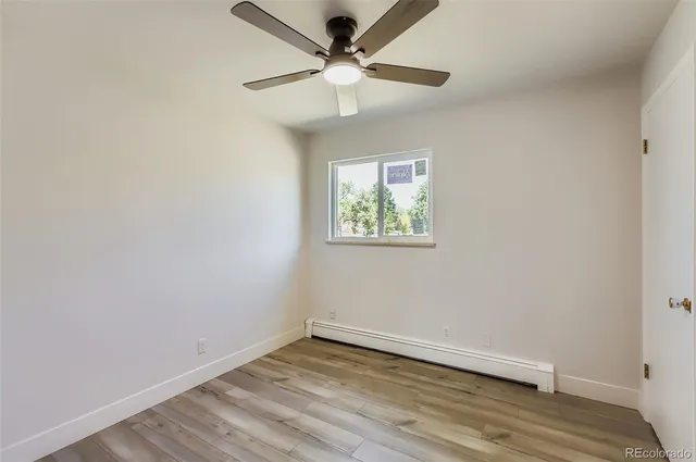 an empty room with wooden floor and ceiling fan