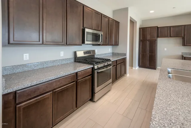 a large kitchen with stainless steel appliances a large counter top a stove and a refrigerator