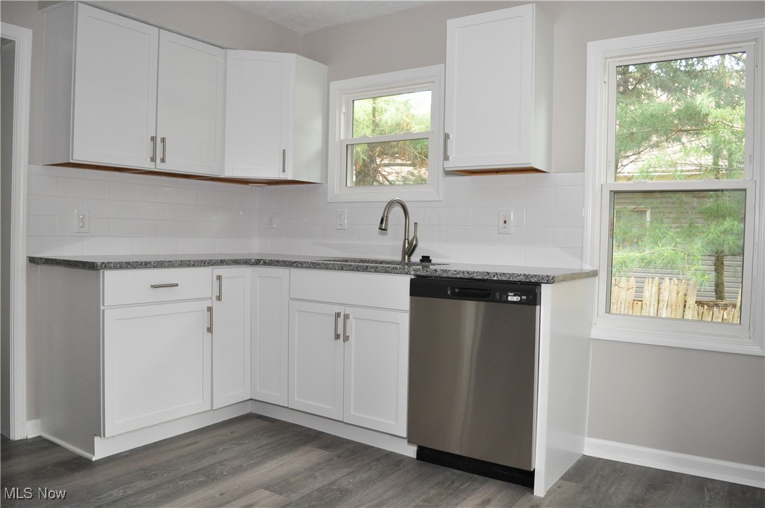 7604 Spafford Road Cleveland, OH 44105 - Photo 16 of 23 Kitchen with stainless steel dishwasher, a sink, tasteful backsplash, white cabinets, and stone countertops
