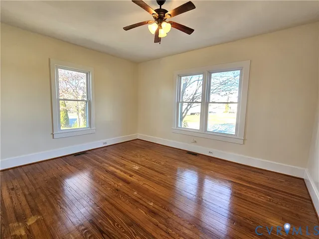 a view of an empty room with window and wooden floor