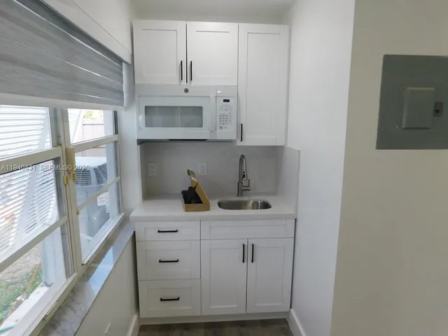 a view of cabinets a sink and a stove in a kitchen