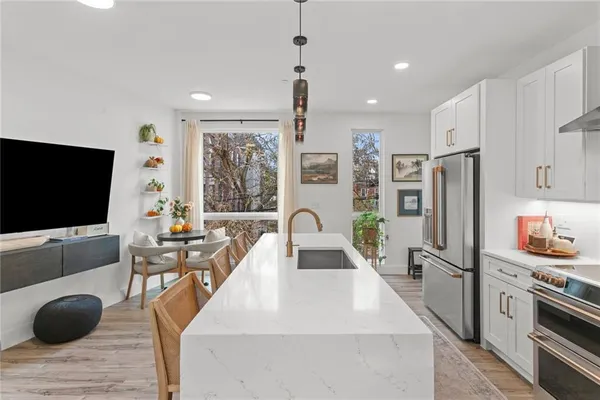 a kitchen with stainless steel appliances kitchen island granite countertop a sink a stove and refrigerator