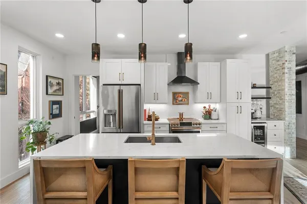 a kitchen with stainless steel appliances granite countertop a refrigerator a stove a sink a dining table and chairs with wooden floor