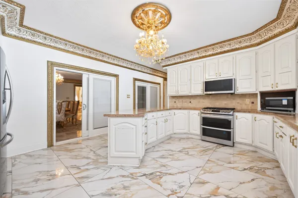 a kitchen with stainless steel appliances granite countertop a stove top oven a sink dishwasher and a refrigerator with wooden floor