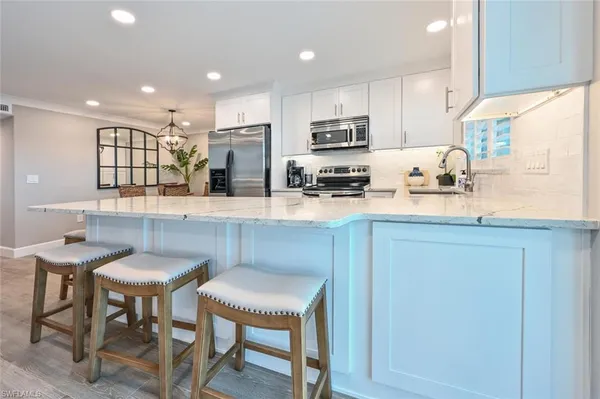 a kitchen with stainless steel appliances granite countertop a table chairs sink refrigerator and microwave