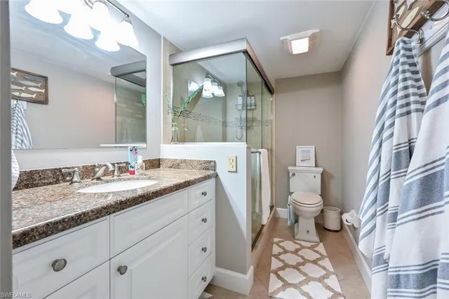 a bathroom with a granite countertop sink toilet and shower