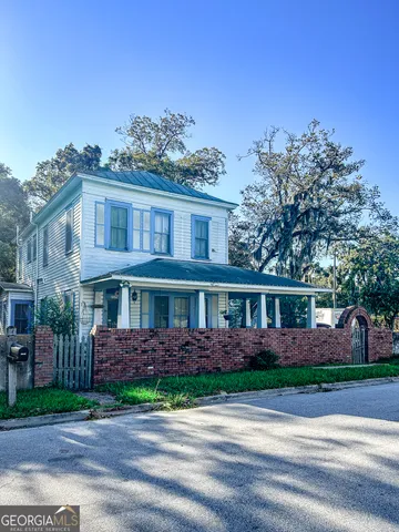 a view of a brick house with a yard and large trees