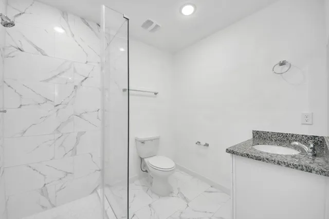 a bathroom with a granite countertop sink a toilet and shower