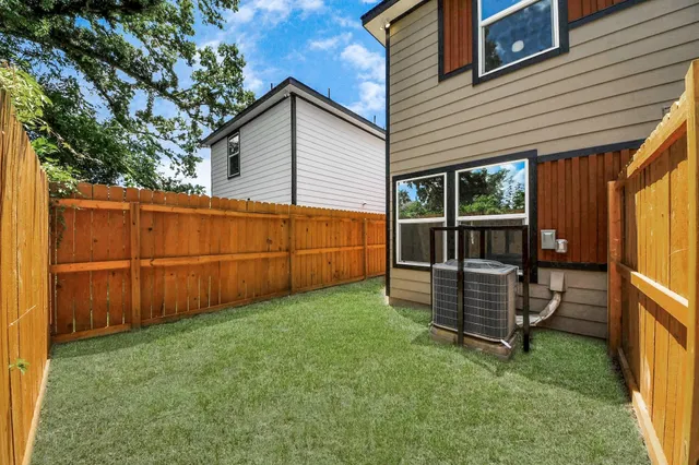 a view of backyard with barbeque grill and wooden fence