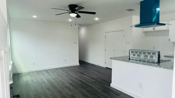 a view of a room with wooden floor and a ceiling fan
