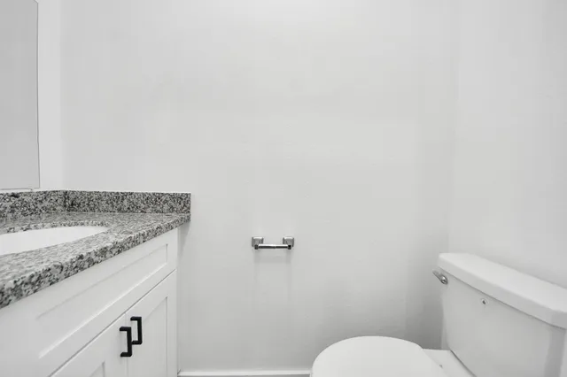 a bathroom with a granite countertop toilet and a sink