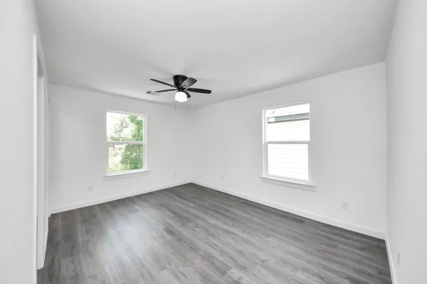 a view of an empty room with a window and wooden floor