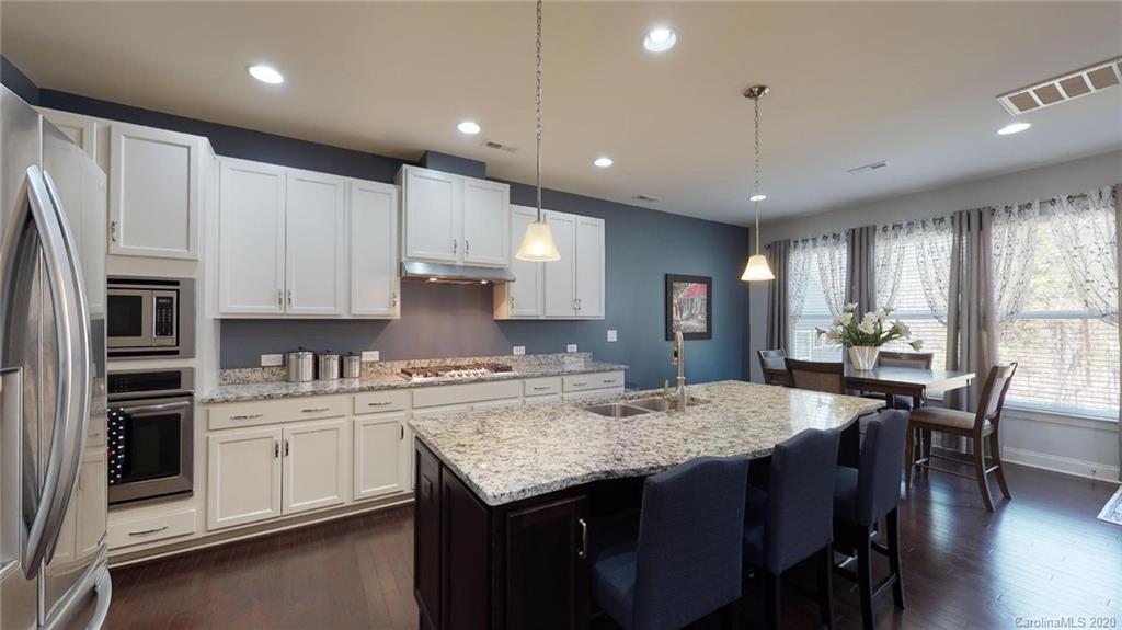 6018 Fallondale Road Waxhaw, NC 28173 - Photo 6 of 48 a kitchen with stainless steel appliances granite countertop a kitchen island hardwood floor sink stove dining table and chairs