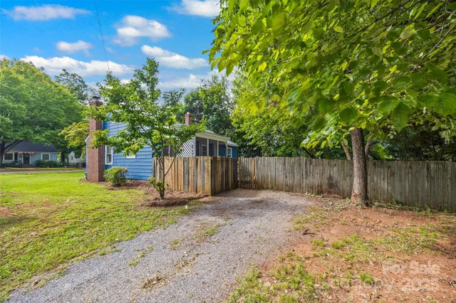 a view of a backyard with large trees and wooden fence