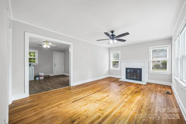 a view of a livingroom with a fireplace a ceiling fan and wooden floor