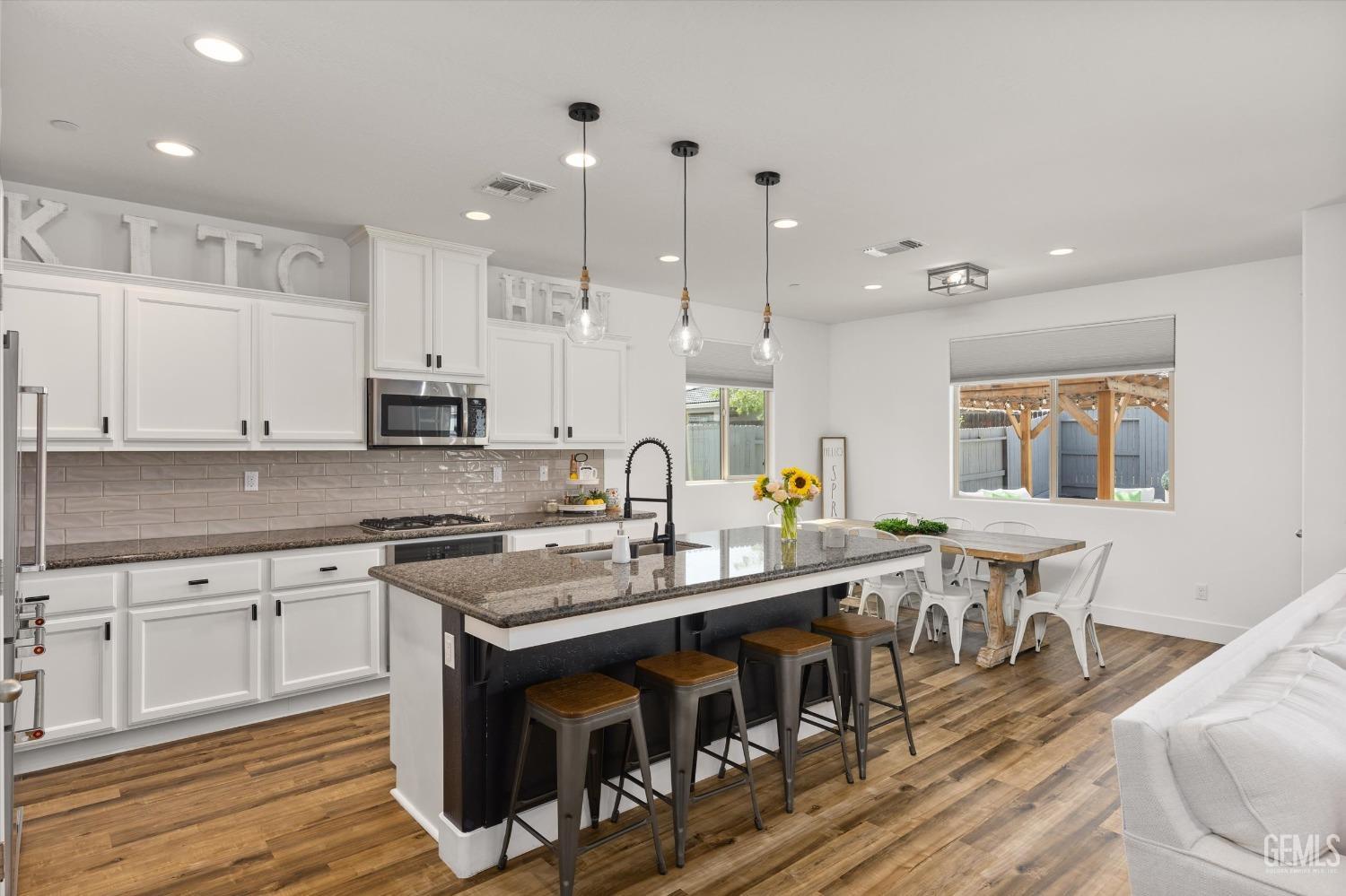 Undisclosed Address Bakersfield, CA 93314 - Photo 9 of 43 a large kitchen with stainless steel appliances granite countertop a stove a sink a dining table and chairs with wooden floor