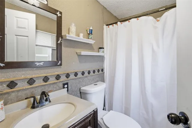 a bathroom with a sink a toilet and shower curtain