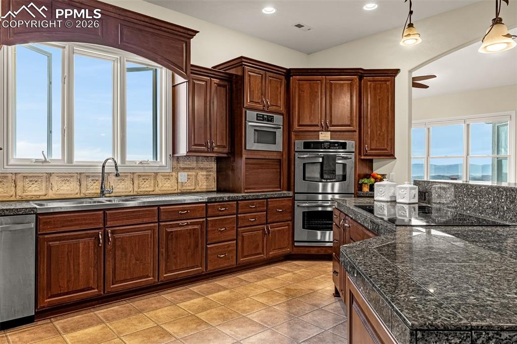 15575 Henry Ride Heights Colorado Springs, CO 80926 - Photo 12 of 46 a kitchen with stainless steel appliances granite countertop a stove and a sink