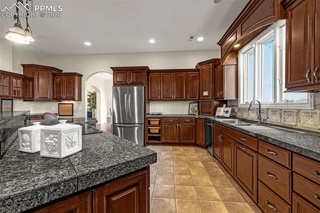 a kitchen with stainless steel appliances granite countertop a sink dishwasher stove refrigerator and cabinets