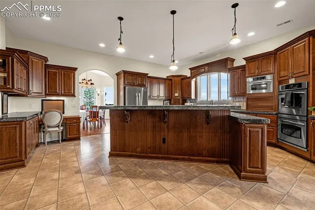 a kitchen with stainless steel appliances granite countertop a stove a sink a oven a dining table and chairs