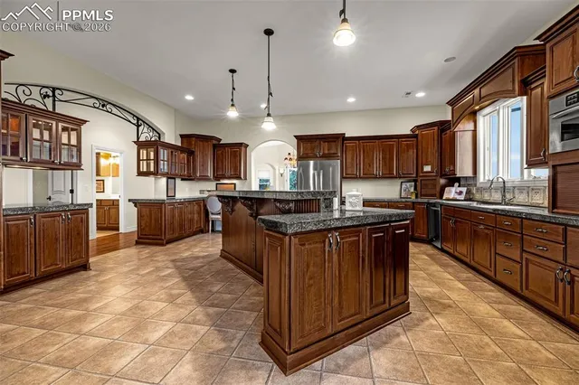 a kitchen with stainless steel appliances granite countertop wooden cabinets a sink a stove a refrigerator and a oven