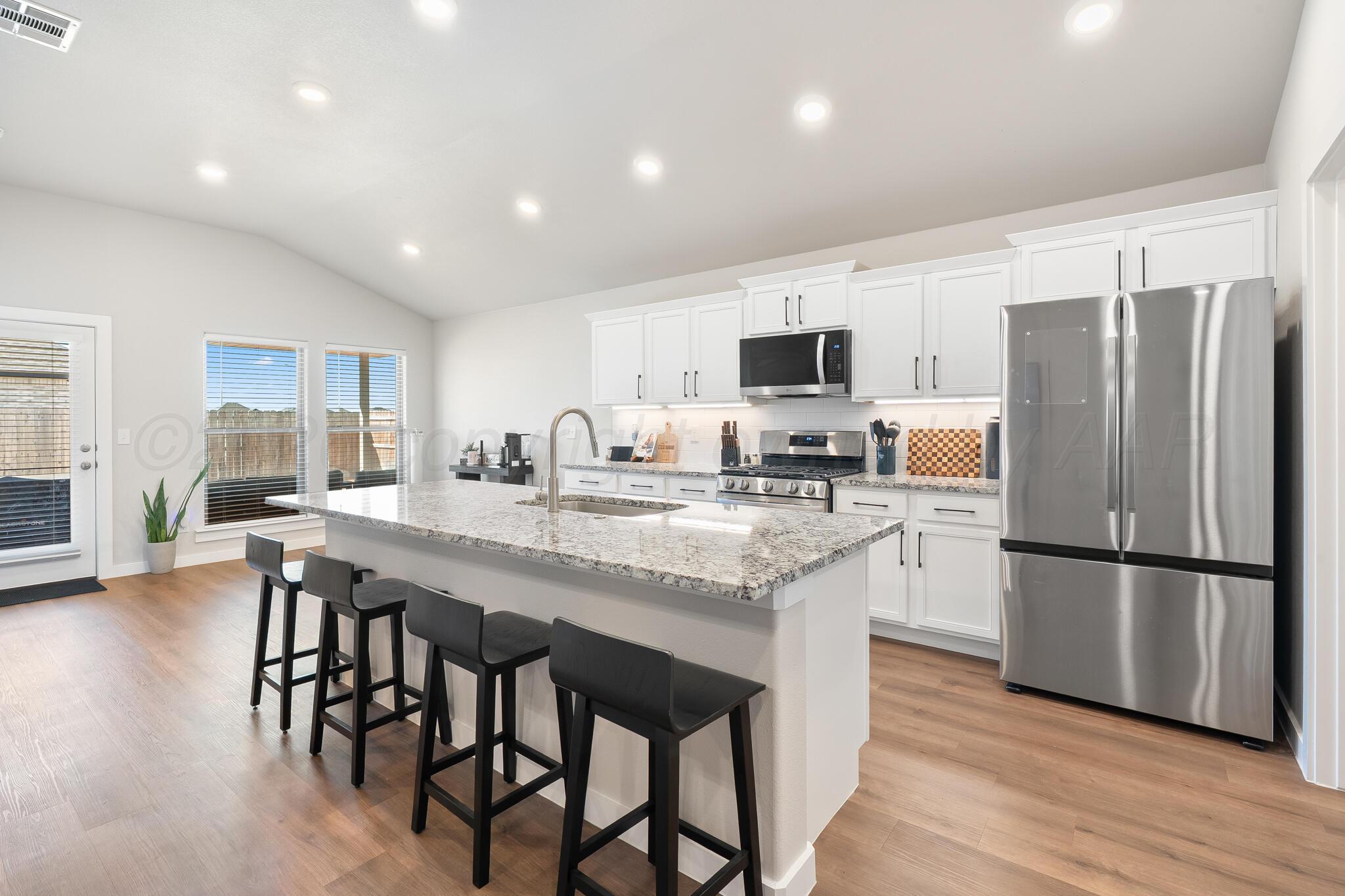 7500 Castleman Road Amarillo, TX 79119 - Photo 7 of 20 a kitchen with stainless steel appliances granite countertop a stove a refrigerator a microwave a sink and a island with wooden floor