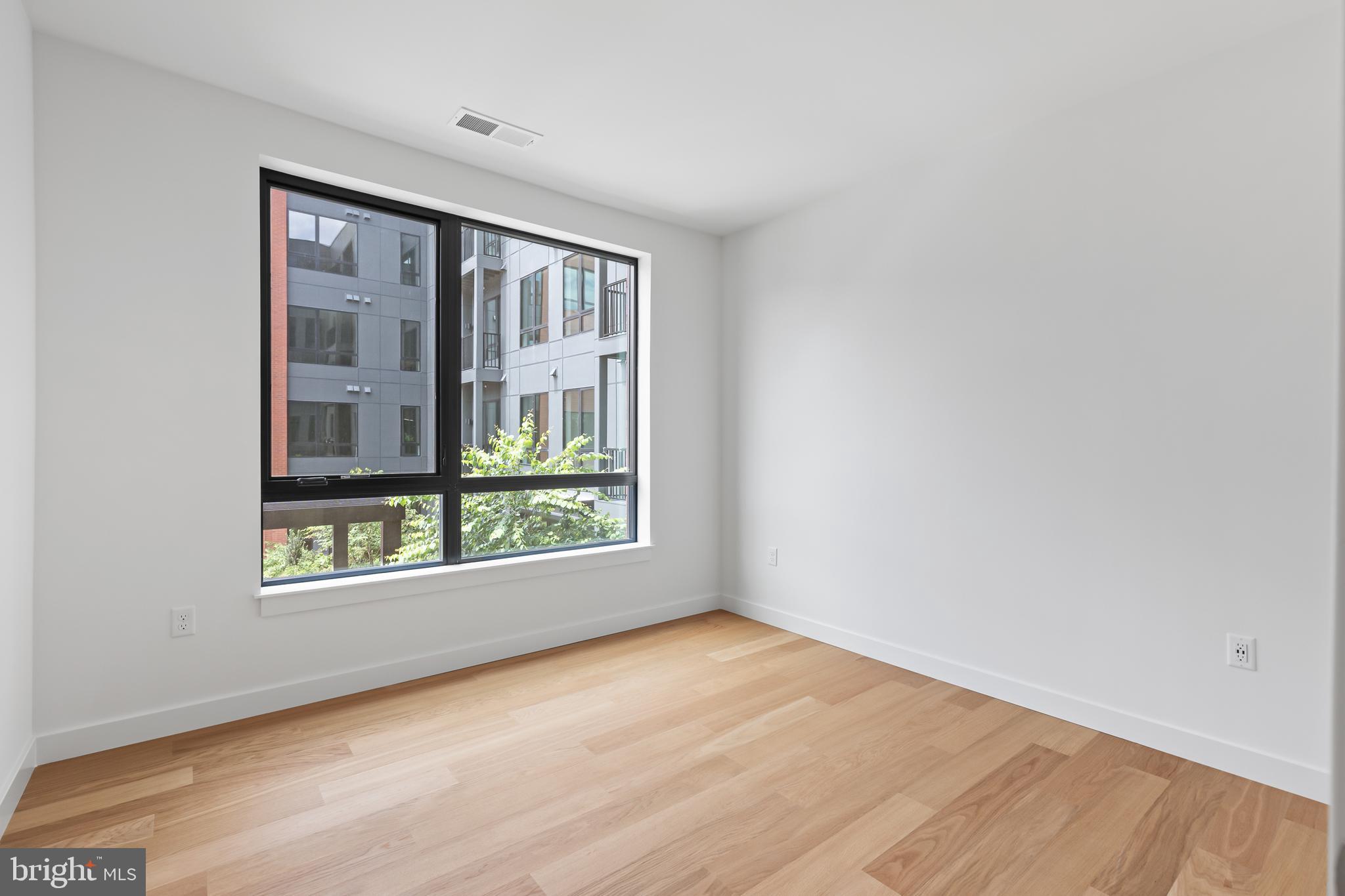 7175 12th Street Northwest, Unit 513 Washington, DC 20012 - Photo 3 of 31 a view of an empty room with a window and wooden floor