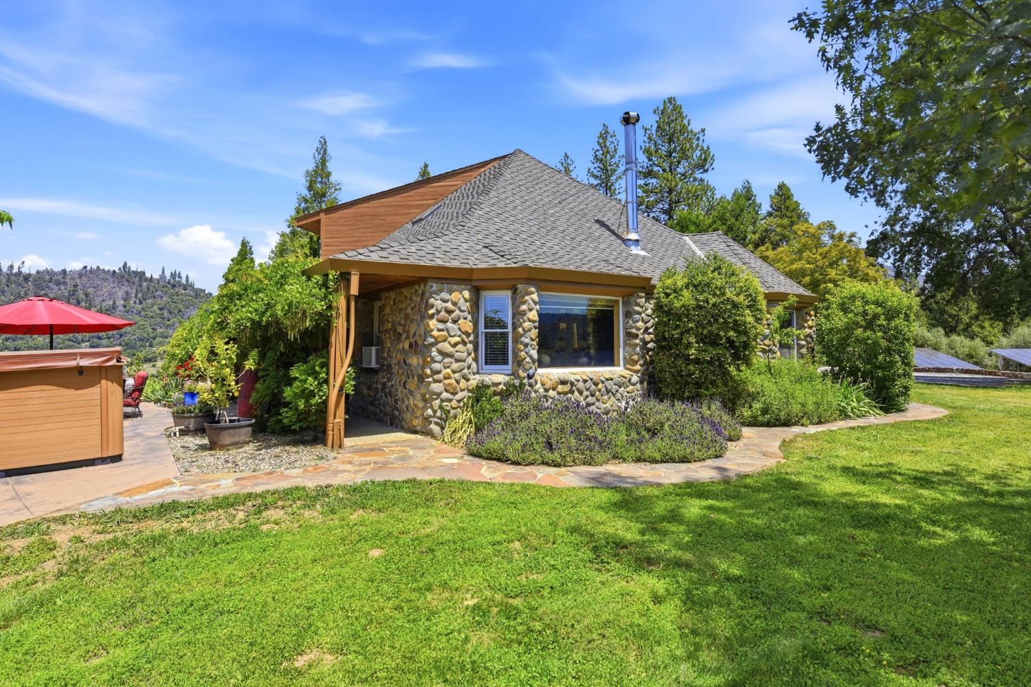 7201 Happy Valley Road Somerset, CA 95684 - Photo 42 of 75 Stone exterior with a gray shingle lifetime composition shingle roof, featuring natural wood posts. This is the side of the house that has the family room window.