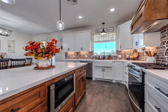 a kitchen with stainless steel appliances granite countertop a sink a stove and a wooden floors
