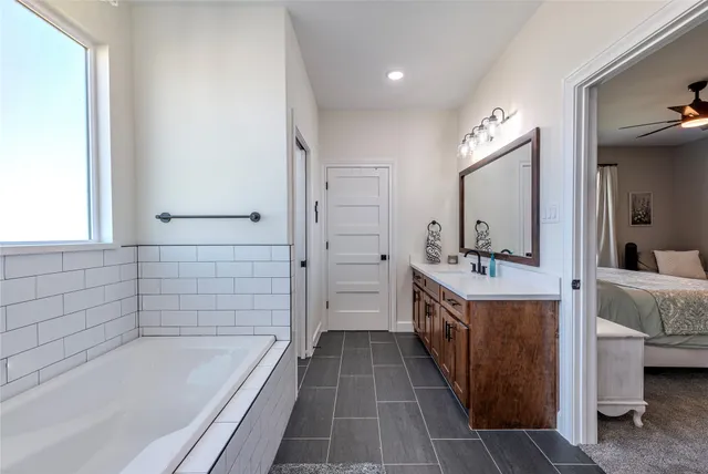 a bathroom with a granite countertop sink a mirror and a bathtub