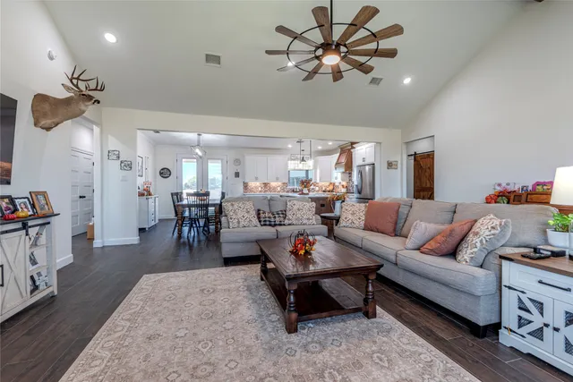 a living room with furniture kitchen view and a chandelier