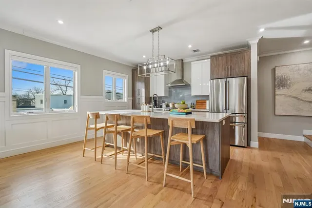 a kitchen with stainless steel appliances granite countertop a table chairs refrigerator and wooden cabinets