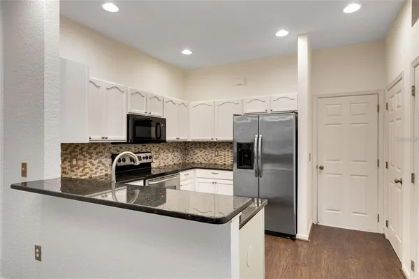 a kitchen with stainless steel appliances granite countertop a refrigerator and a sink