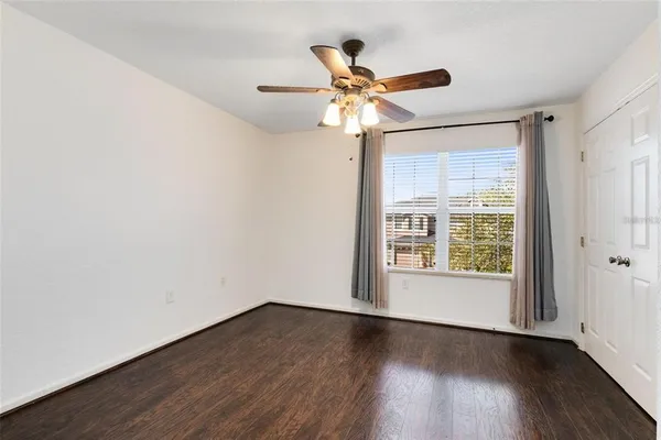 a view of empty room with wooden floor and fan