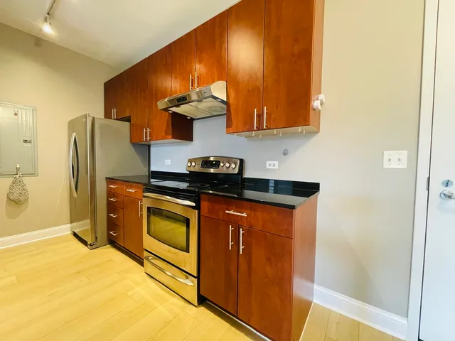 a kitchen with stainless steel appliances granite countertop a refrigerator a stove and a sink