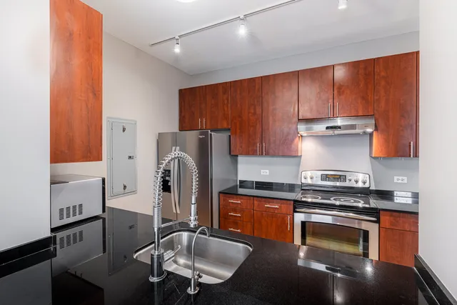 a kitchen with granite countertop a stove refrigerator and sink