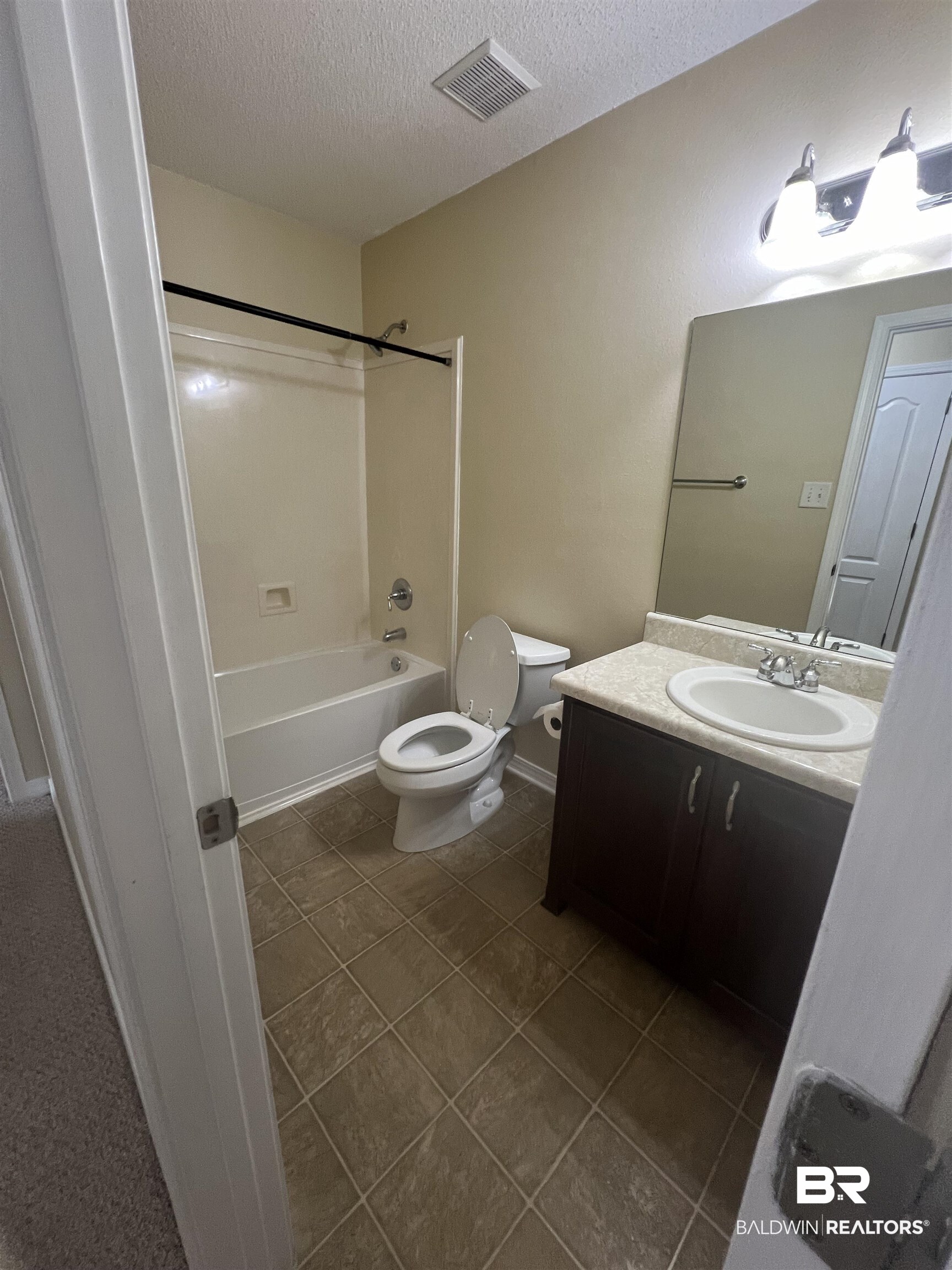 17793 Fancy Boulevard Foley, AL 36535 - Photo 13 of 34 Full bathroom with tile patterned flooring, vanity, shower combination, toilet, and a textured ceiling