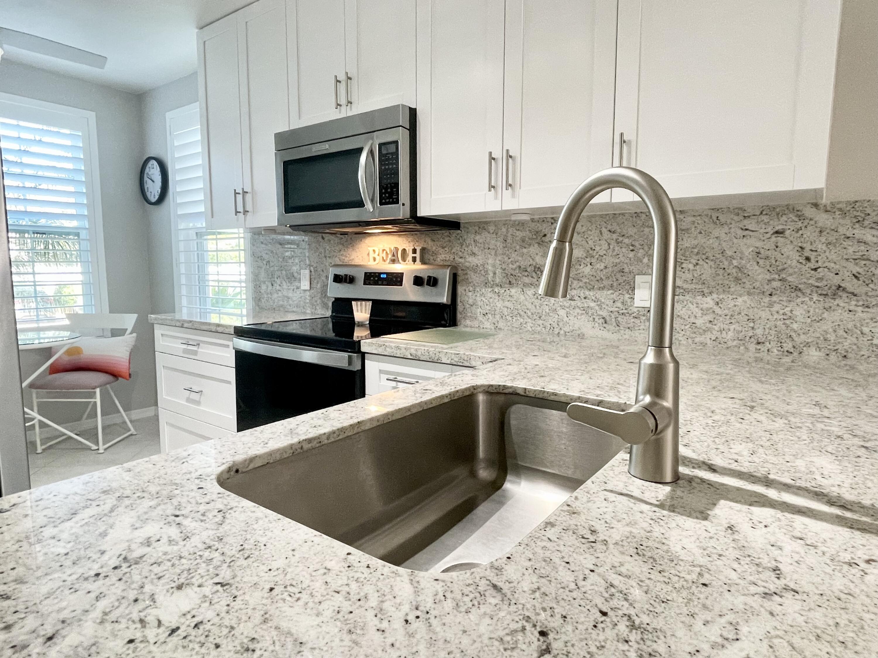 960 Huron Street, Unit 106 Marco Island, FL 34145 - Photo 11 of 39 a kitchen with stainless steel appliances granite countertop a stove a sink and a microwave