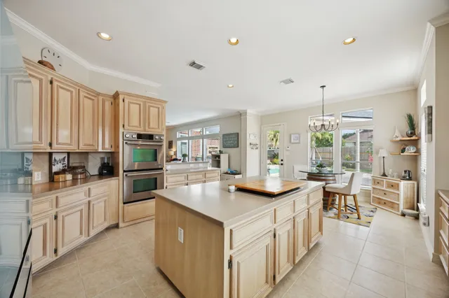 a kitchen that has a lot of white cabinets and stainless steel appliances