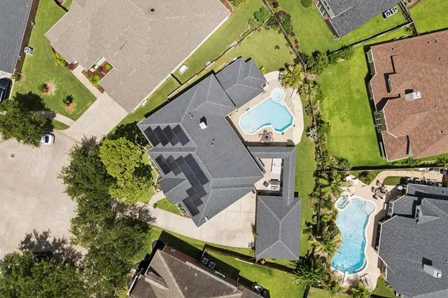 an aerial view of a house with a yard and a large tree